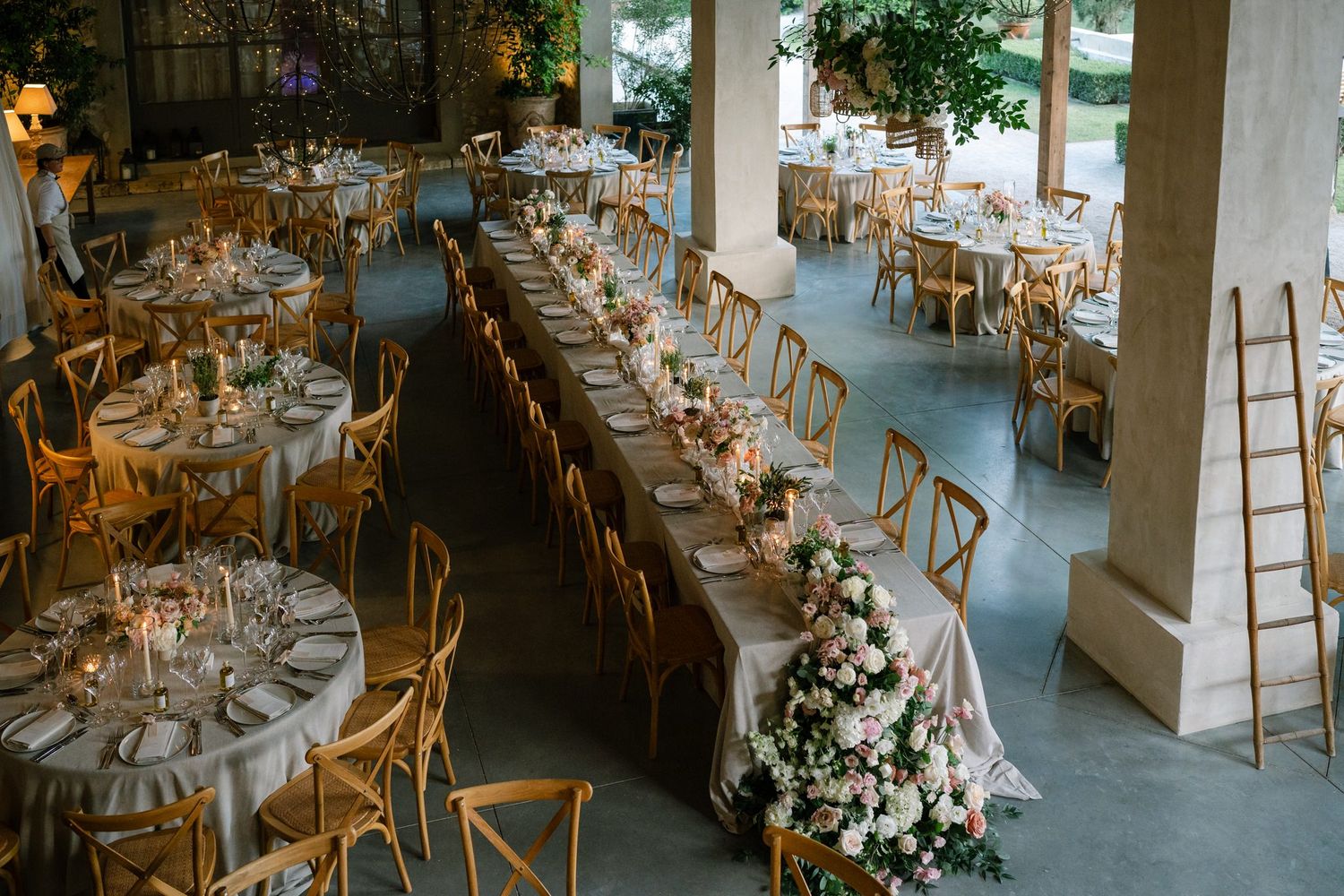 Overhead view of an elegant wedding reception venue with cross-back chairs and floral arrangements.