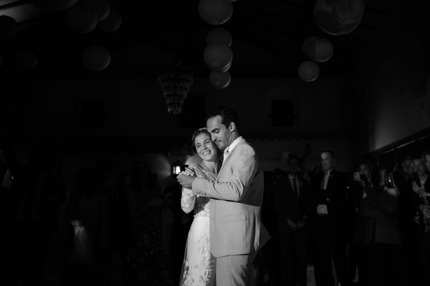 Silhouettes of dancing guests celebrating at a dimly lit wedding reception.
