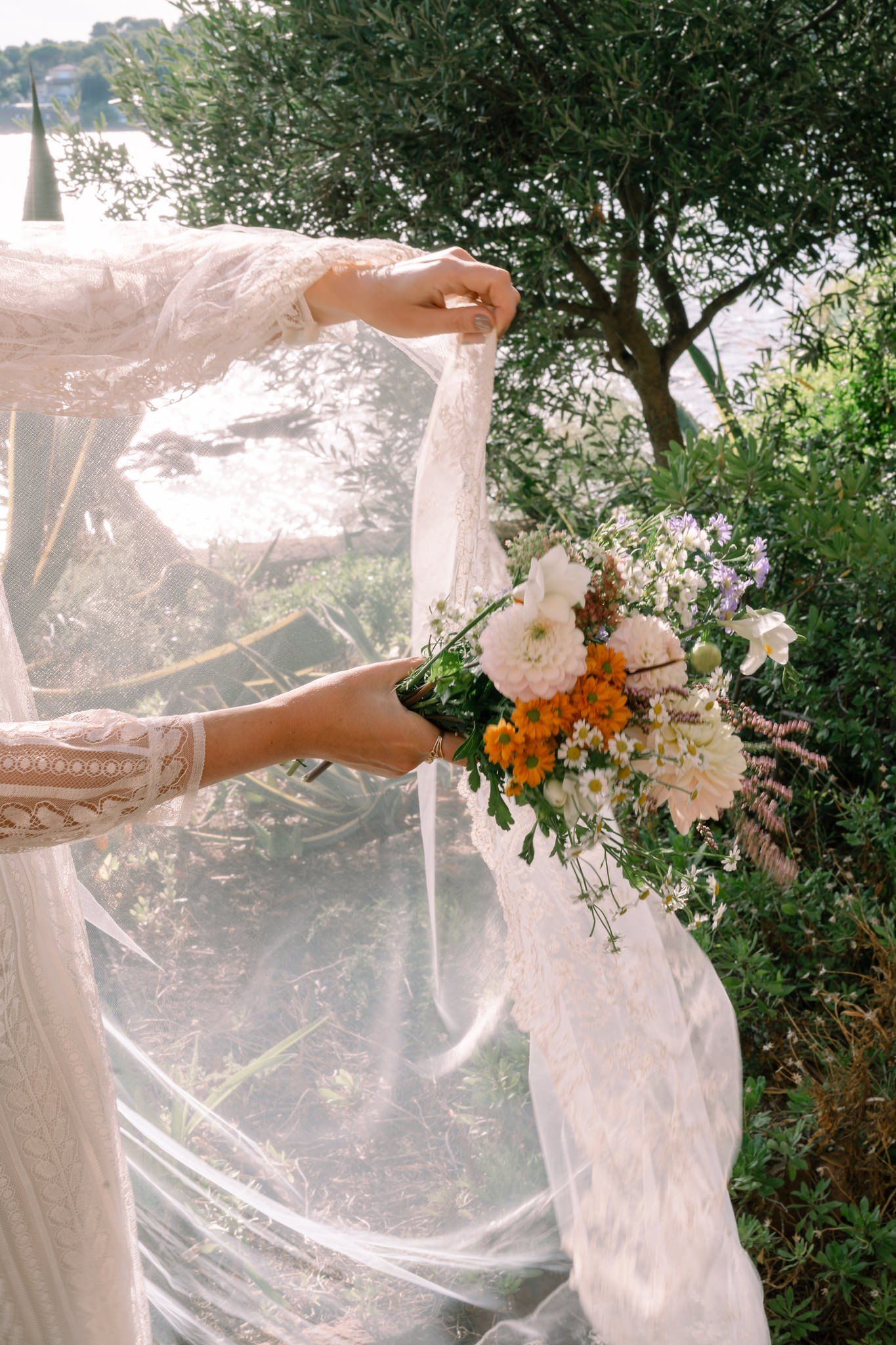 A dreamy wedding veil flows in the breeze during an outdoor photoshoot with floral arrangements.