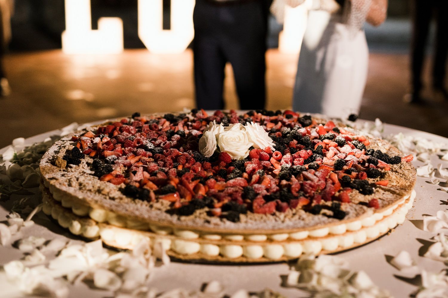 Dessert table featuring berry-topped pastries and cakes at an elegant wedding reception.