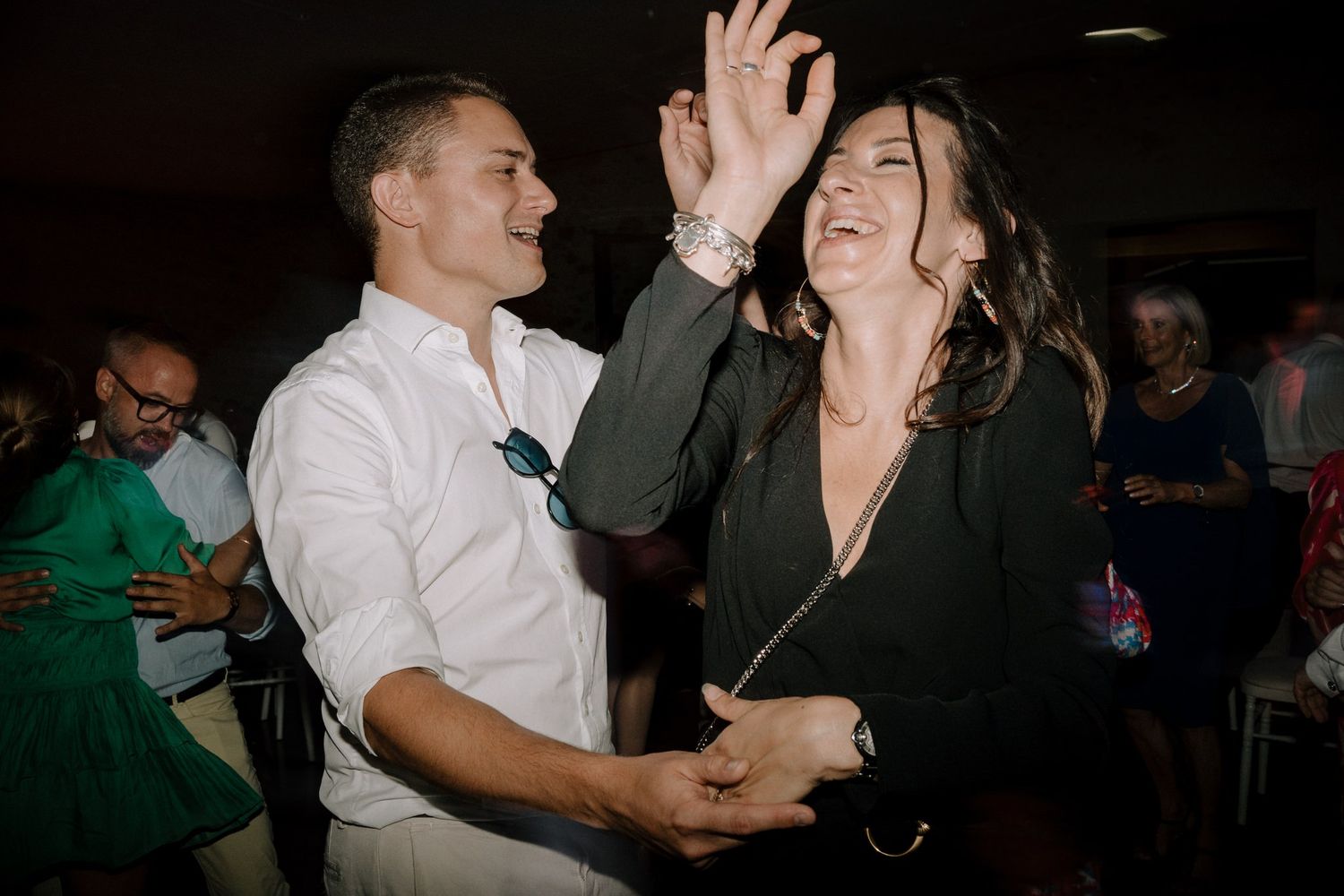 Couples dancing together at an evening celebration in a dark venue.