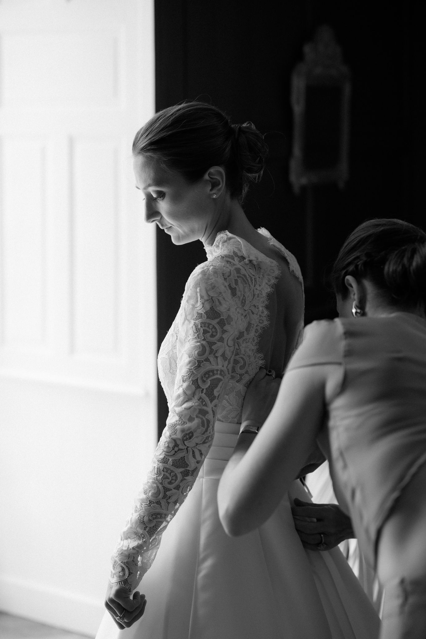 Elegant lace detail on white wedding dress captured in dramatic lighting.