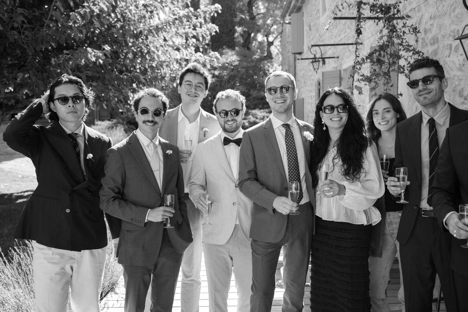 Wedding guests wearing sunglasses and formal attire enjoying an outdoor celebration.