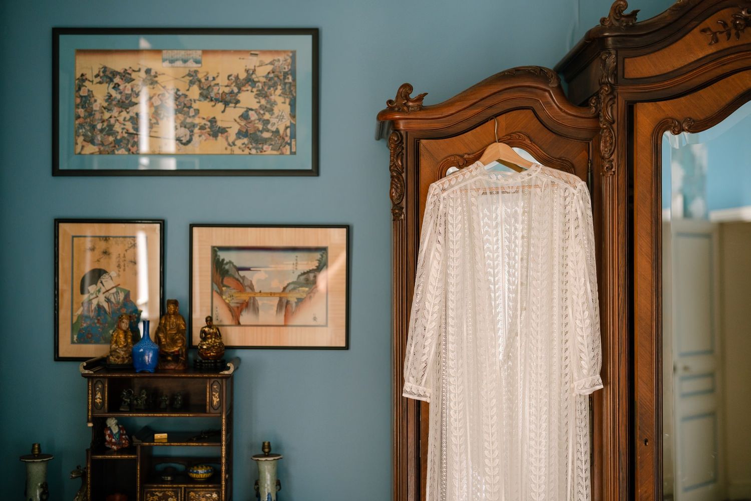 Vintage furniture and artwork in a room with teal blue walls and white trim.