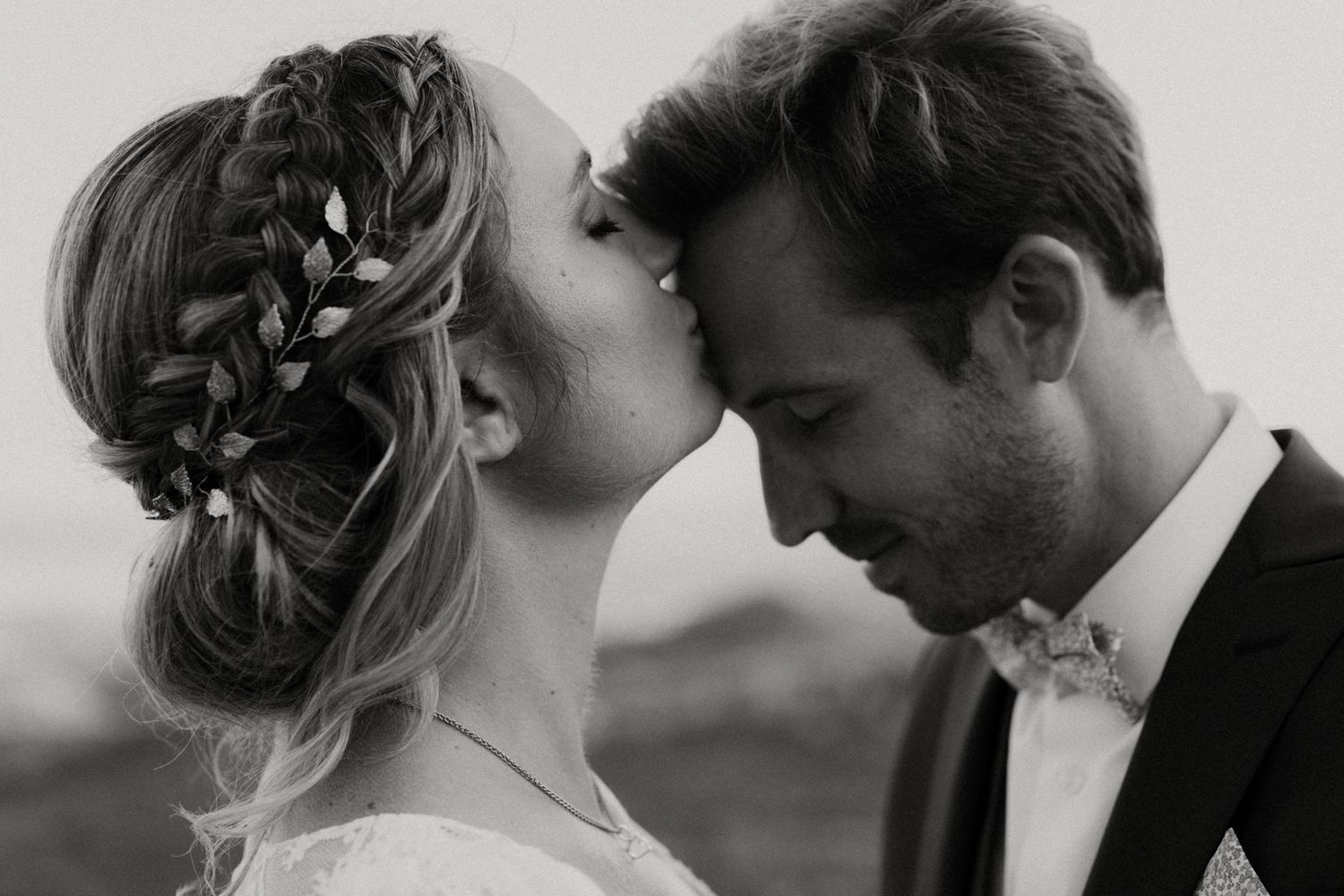 Intimate black and white portrait of newlyweds with elegant braided hairstyle.