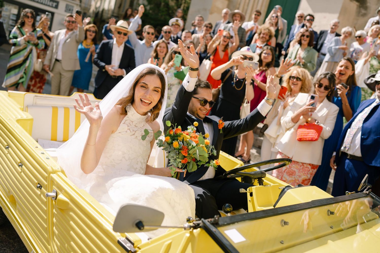 Wedding guests celebrate with confetti and cheers during an outdoor ceremony.