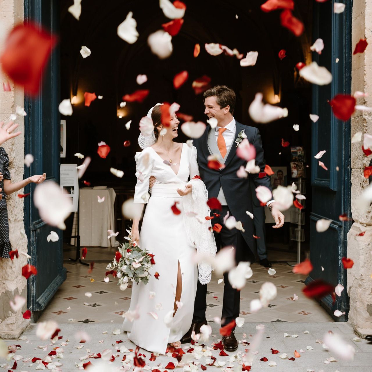 Red and white flower petals falling during an indoor wedding celebration.