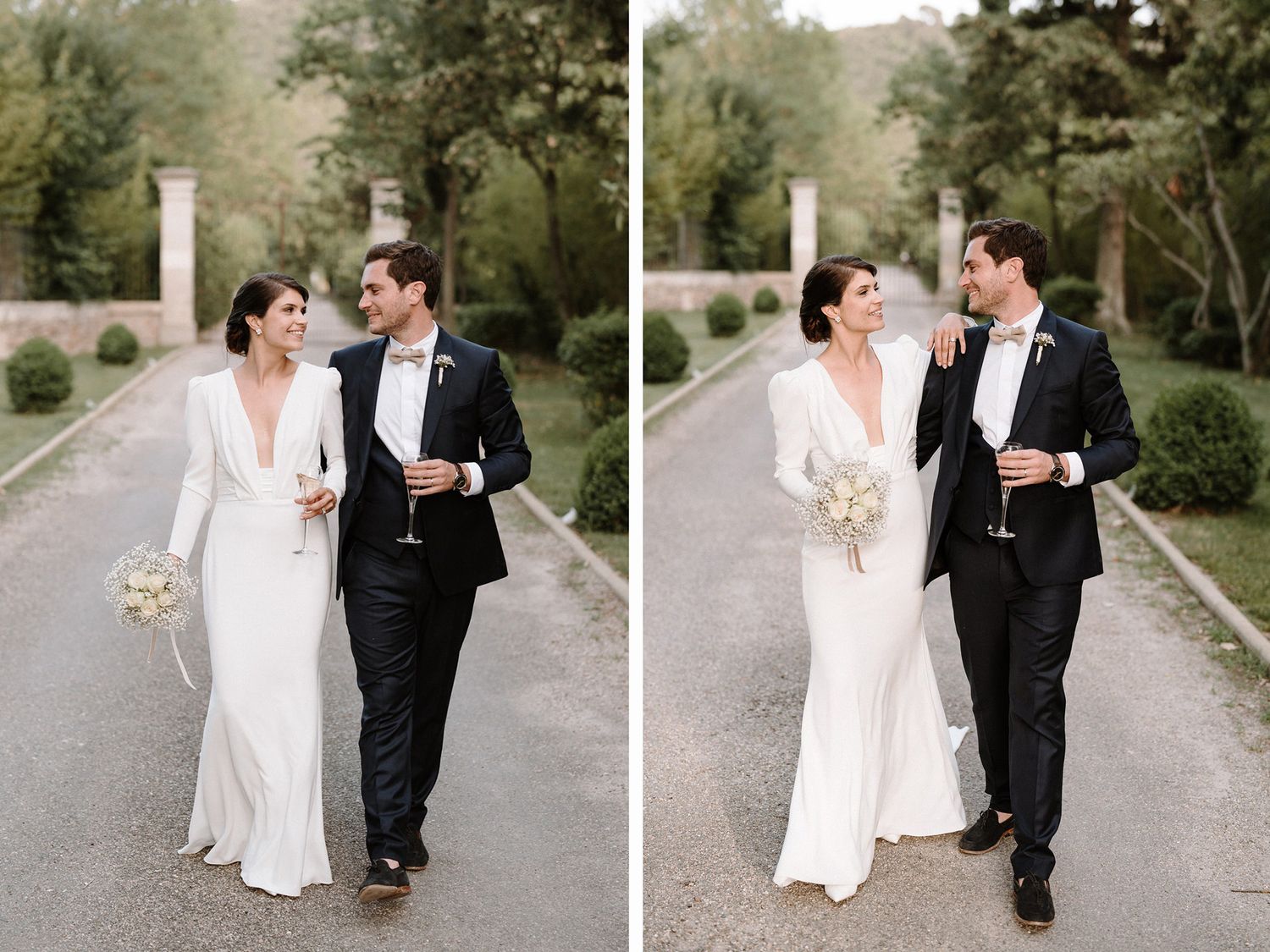 A couple walks together along a tree-lined path in romantic wedding attire.
