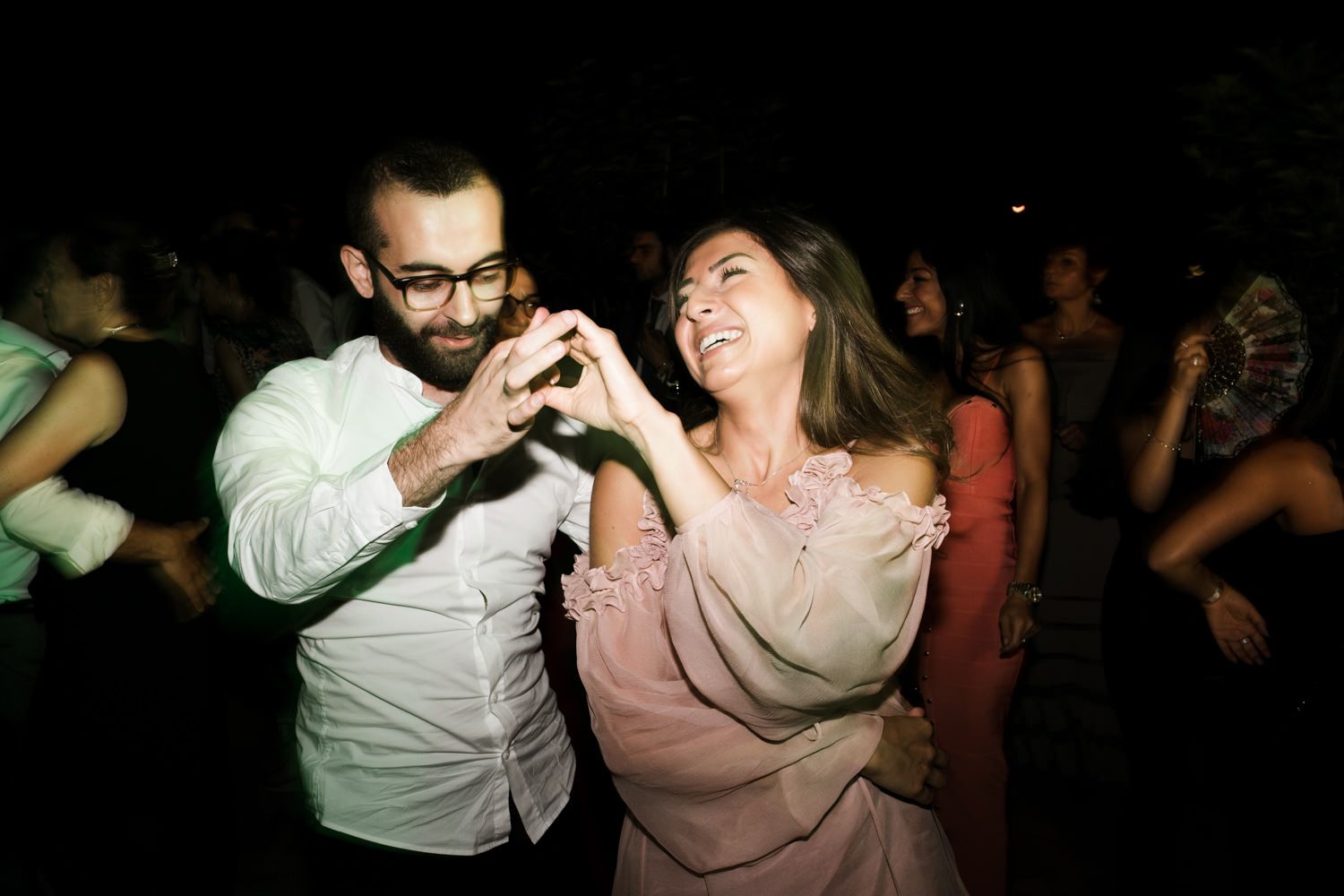 Couples dancing together at a dimly lit indoor party venue.