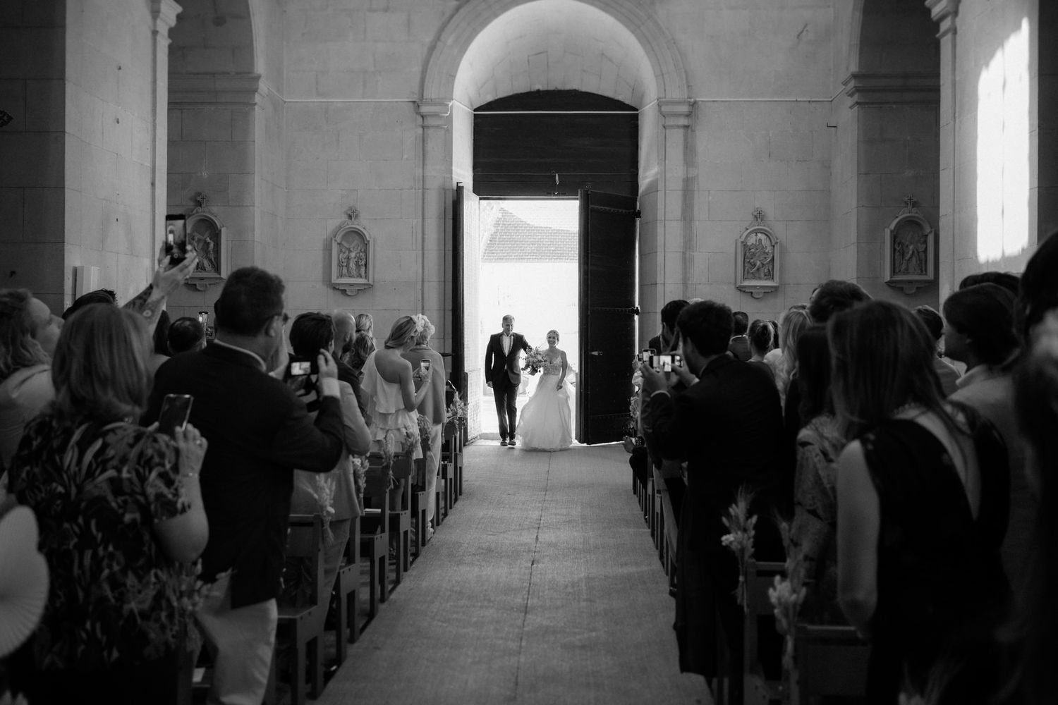 Wedding ceremony in a traditional church with guests seated in wooden pews and natural light streaming through windows.
