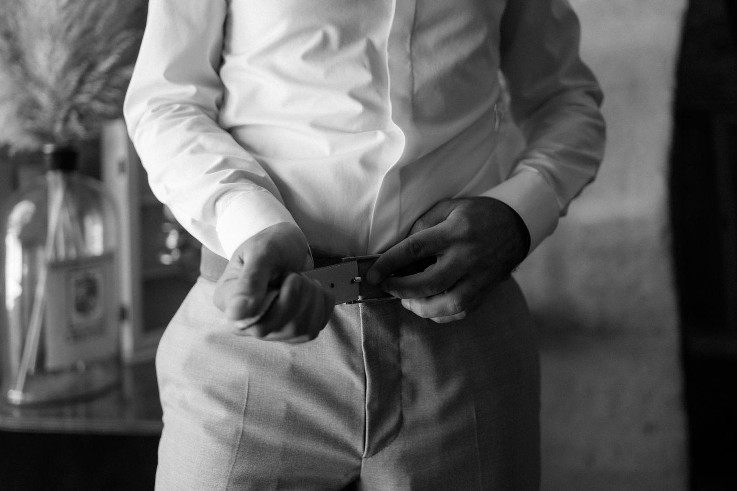 Black and white close-up of hands adjusting formal wear details.