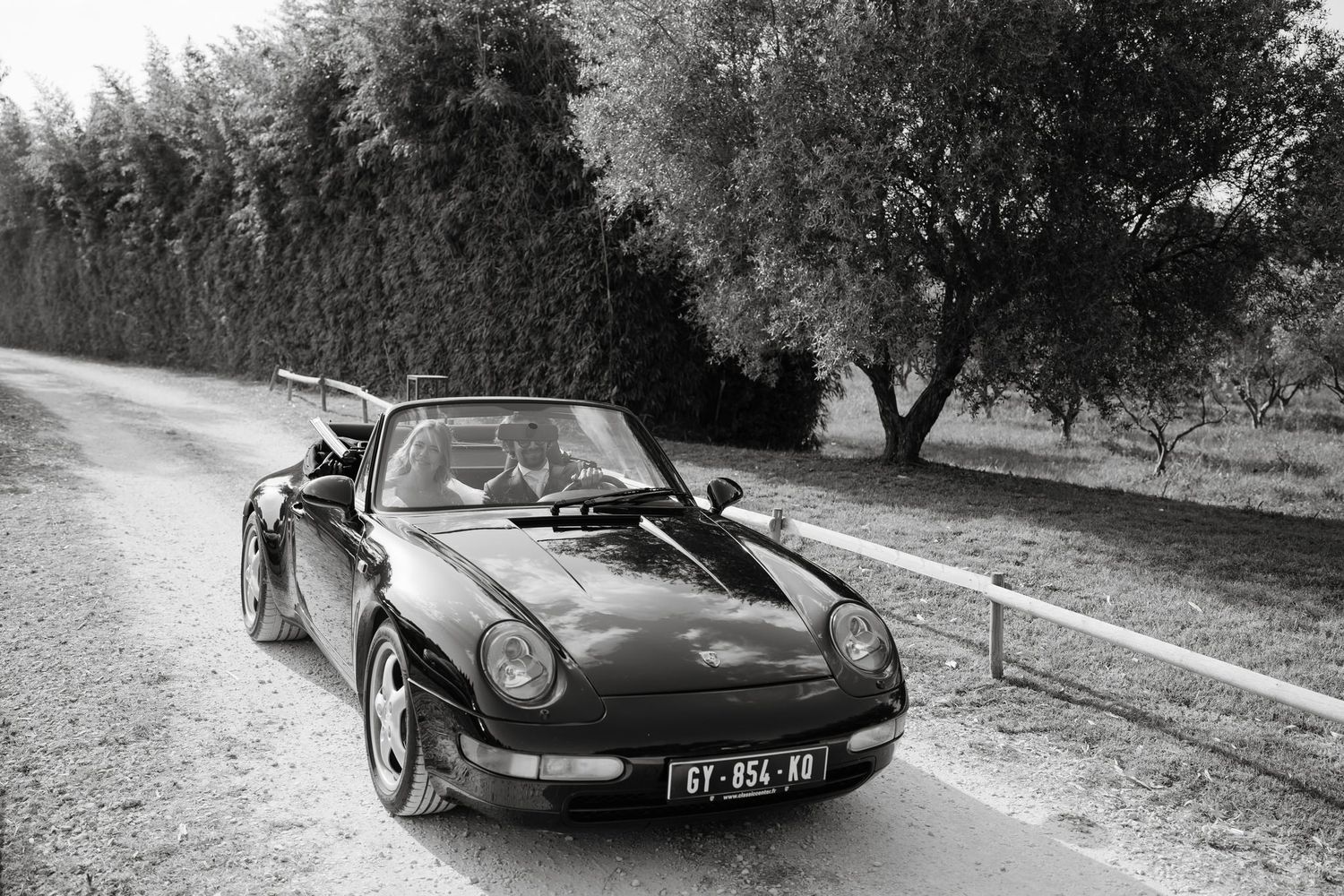 Classic black vintage Porsche sports car parked on rural road for wedding transportation.
