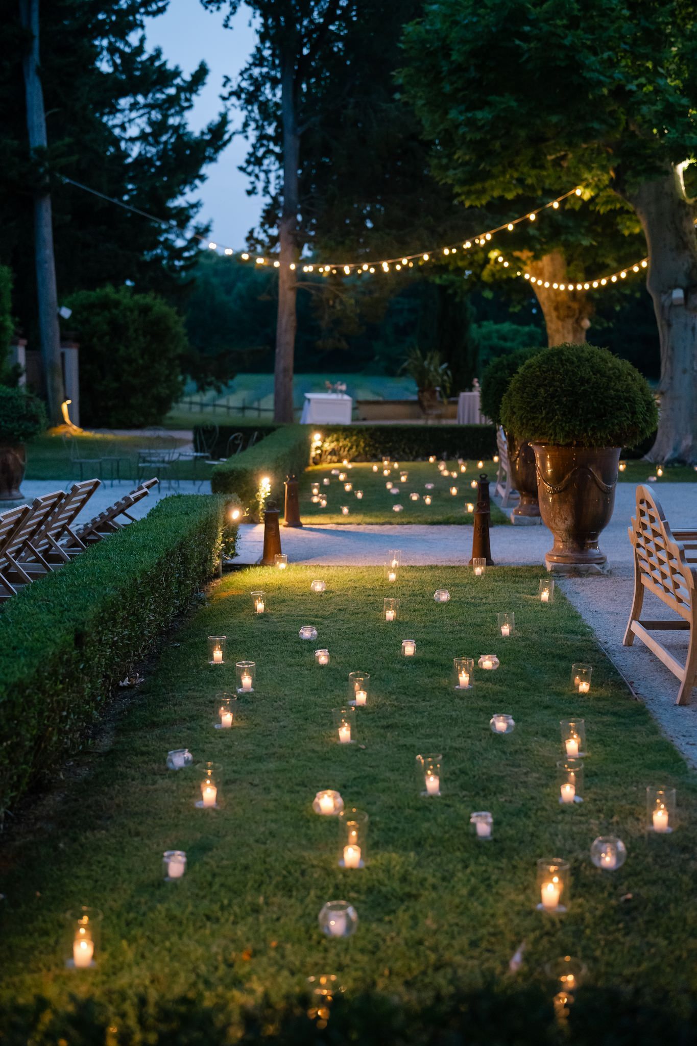 Garden pathway lined with glowing lanterns and string lights creating magical evening ambiance.
