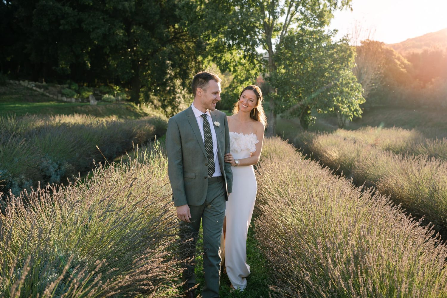 A couple shares an intimate moment in a field during golden hour.