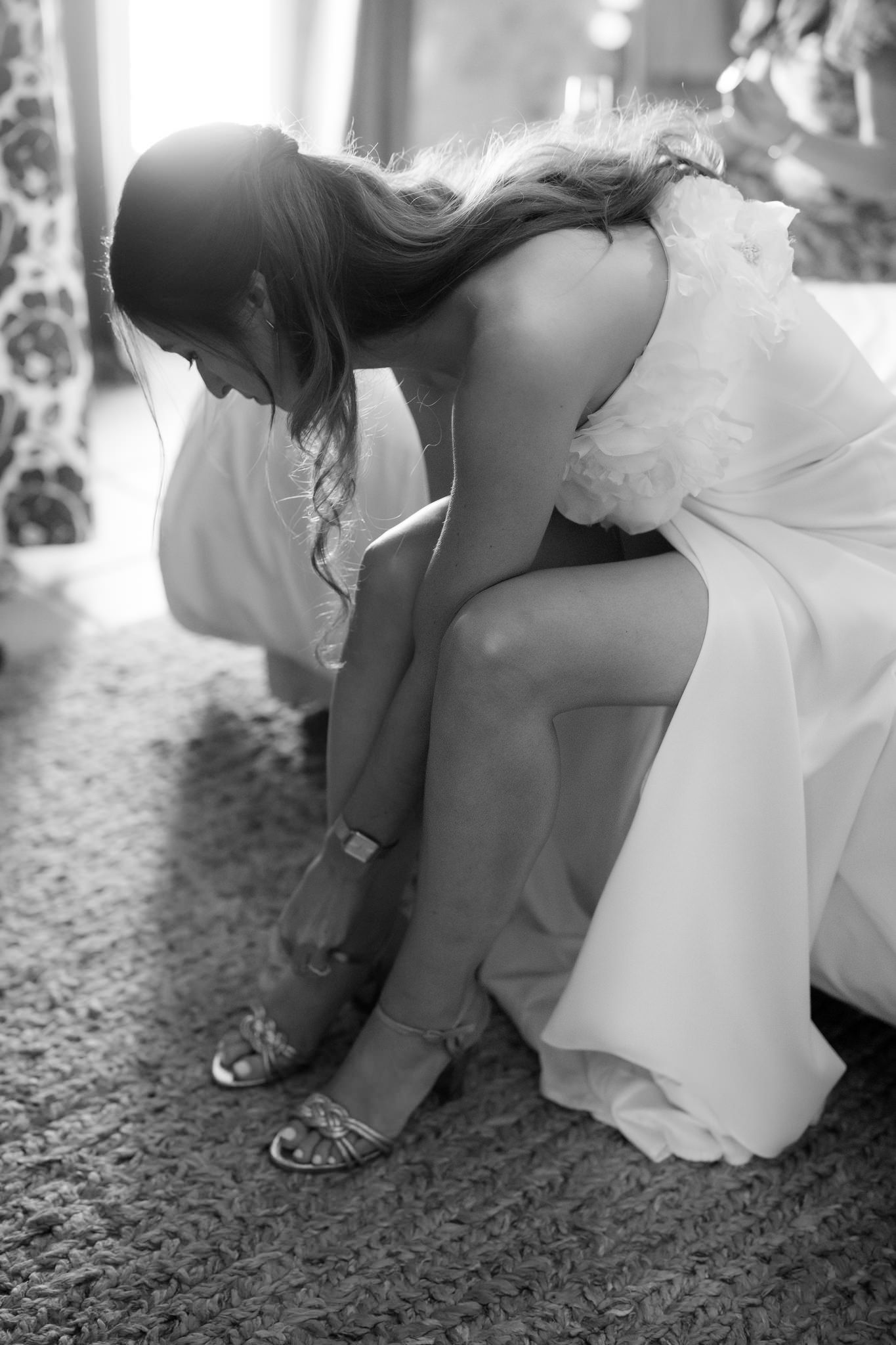 Wedding party members adjusting their shoes and dresses before the ceremony.