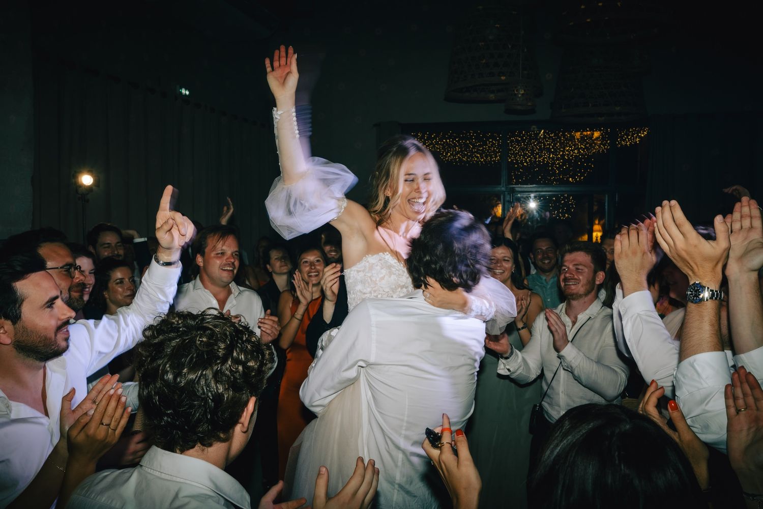 Energetic crowd dancing and celebrating at a lively party with raised hands and joyful expressions.