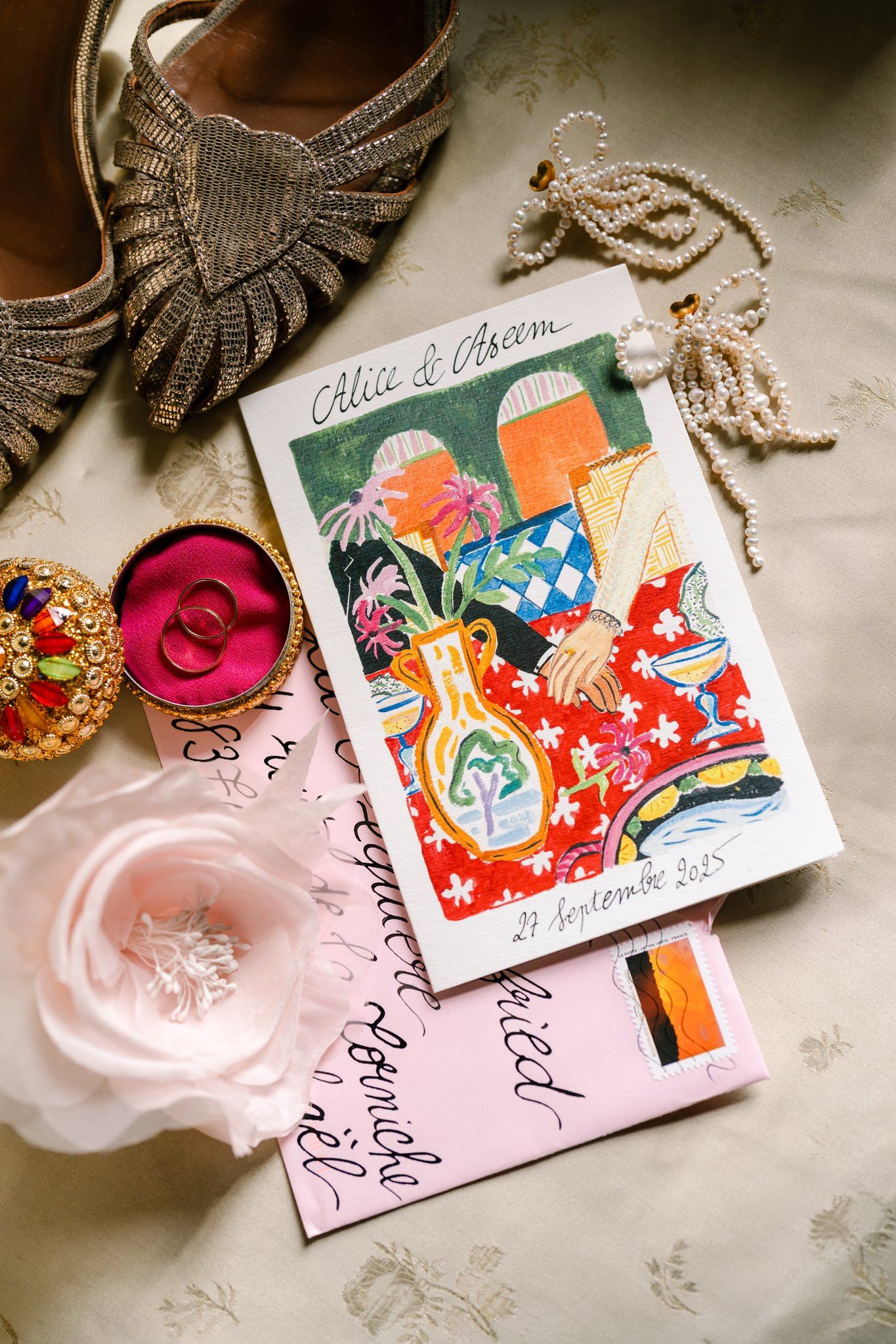 Wedding stationery with colorful floral designs and pink accents laid out on table.