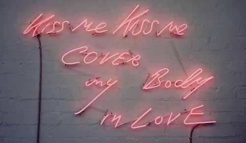 Pink neon sign text glowing against dark wall.