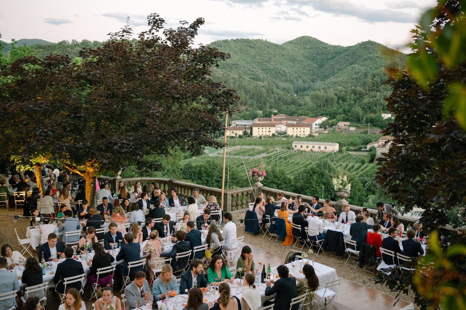 Outdoor wedding ceremony setup with mountain views and guests seated in white chairs.