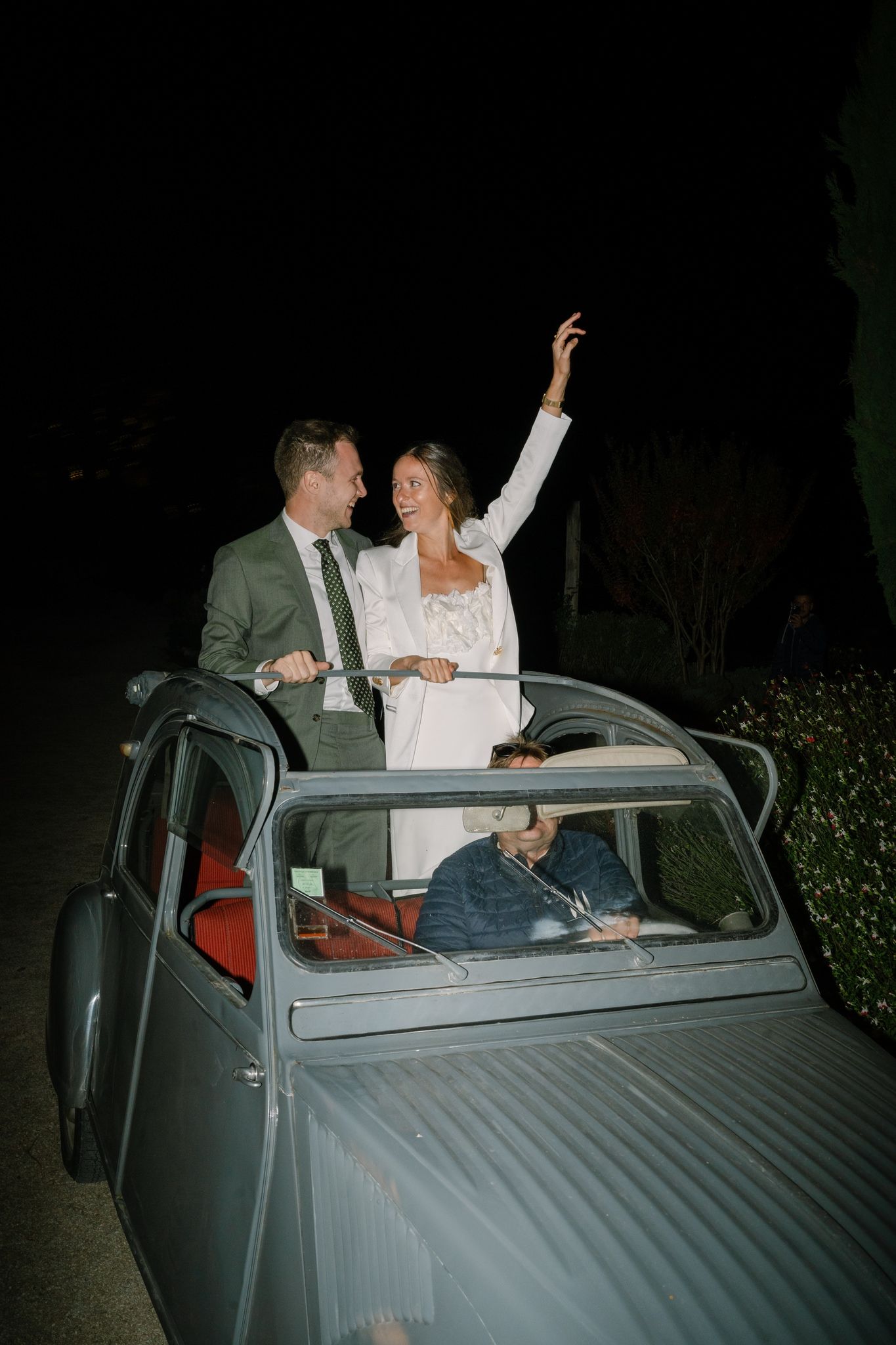 A couple celebrates in the back of a vintage car during their wedding night.