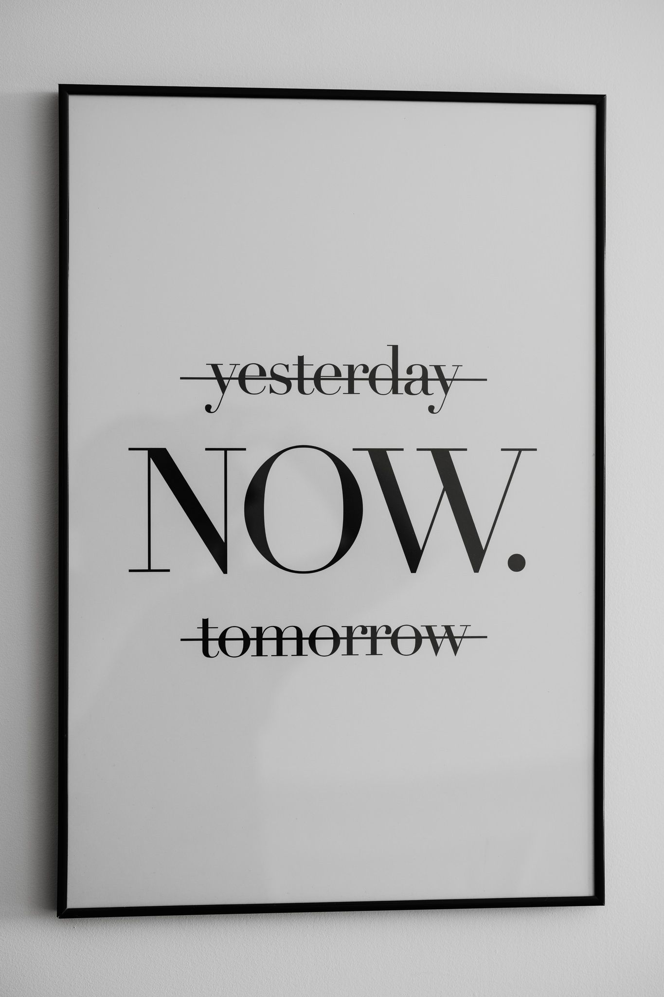 Minimalist wall art showing the word NOW with yesterday and tomorrow crossed out.
