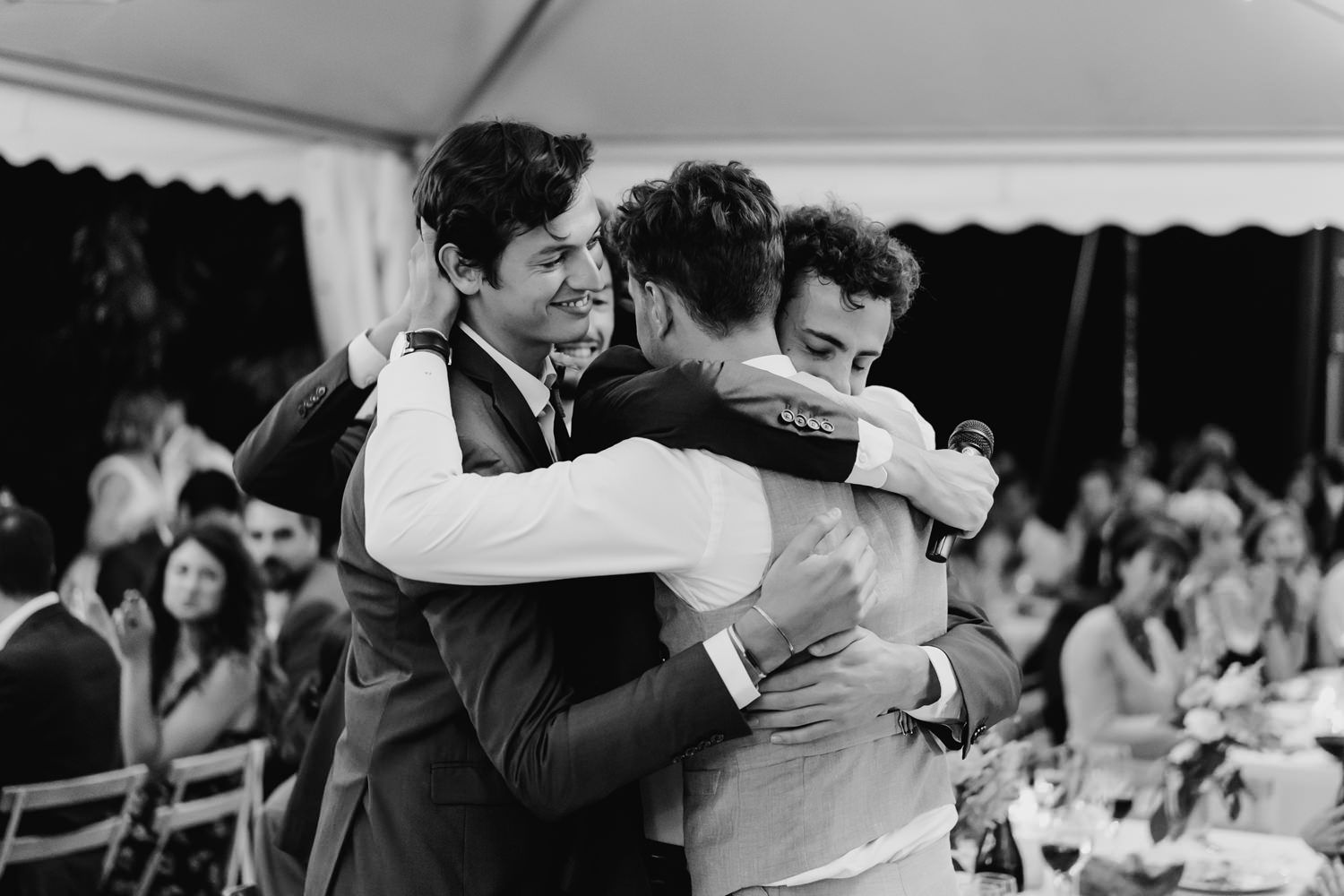 Wedding guests embracing and celebrating during reception festivities.
