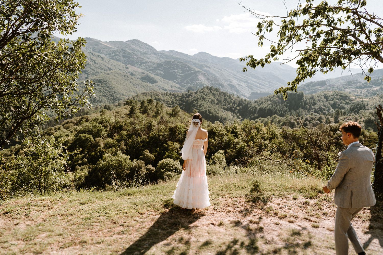 Wedding couple standing on a mountain overlook with dramatic landscape views in the background.