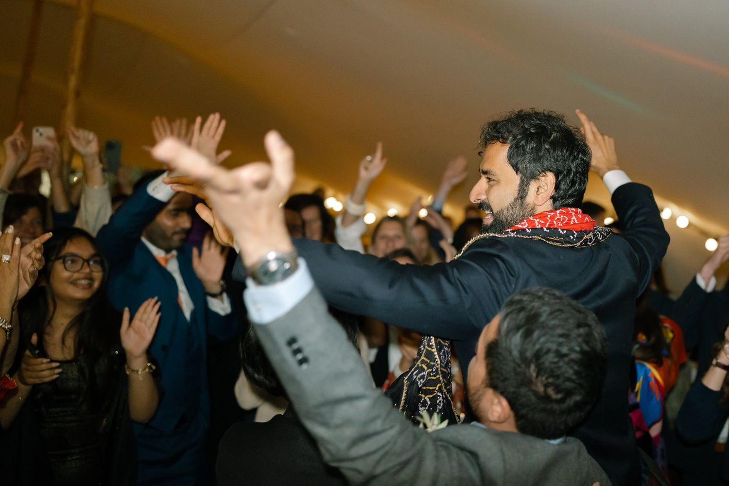 Guests dancing with raised hands during an energetic wedding reception celebration.