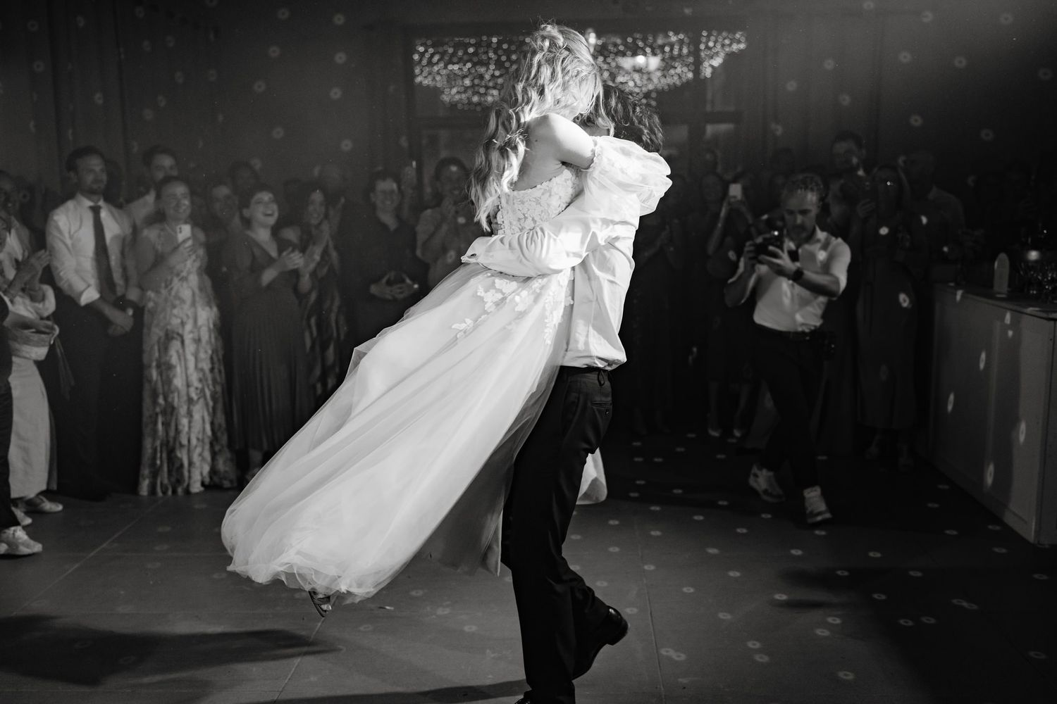 Black and white photo of wedding guests dancing and celebrating on the dance floor.
