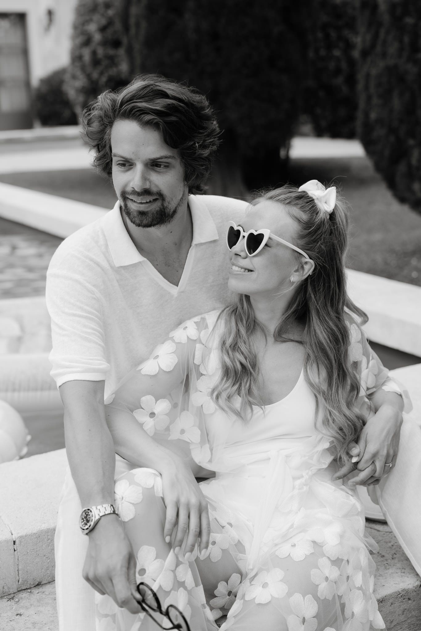 Couple in white summer attire sharing a romantic moment outdoors.