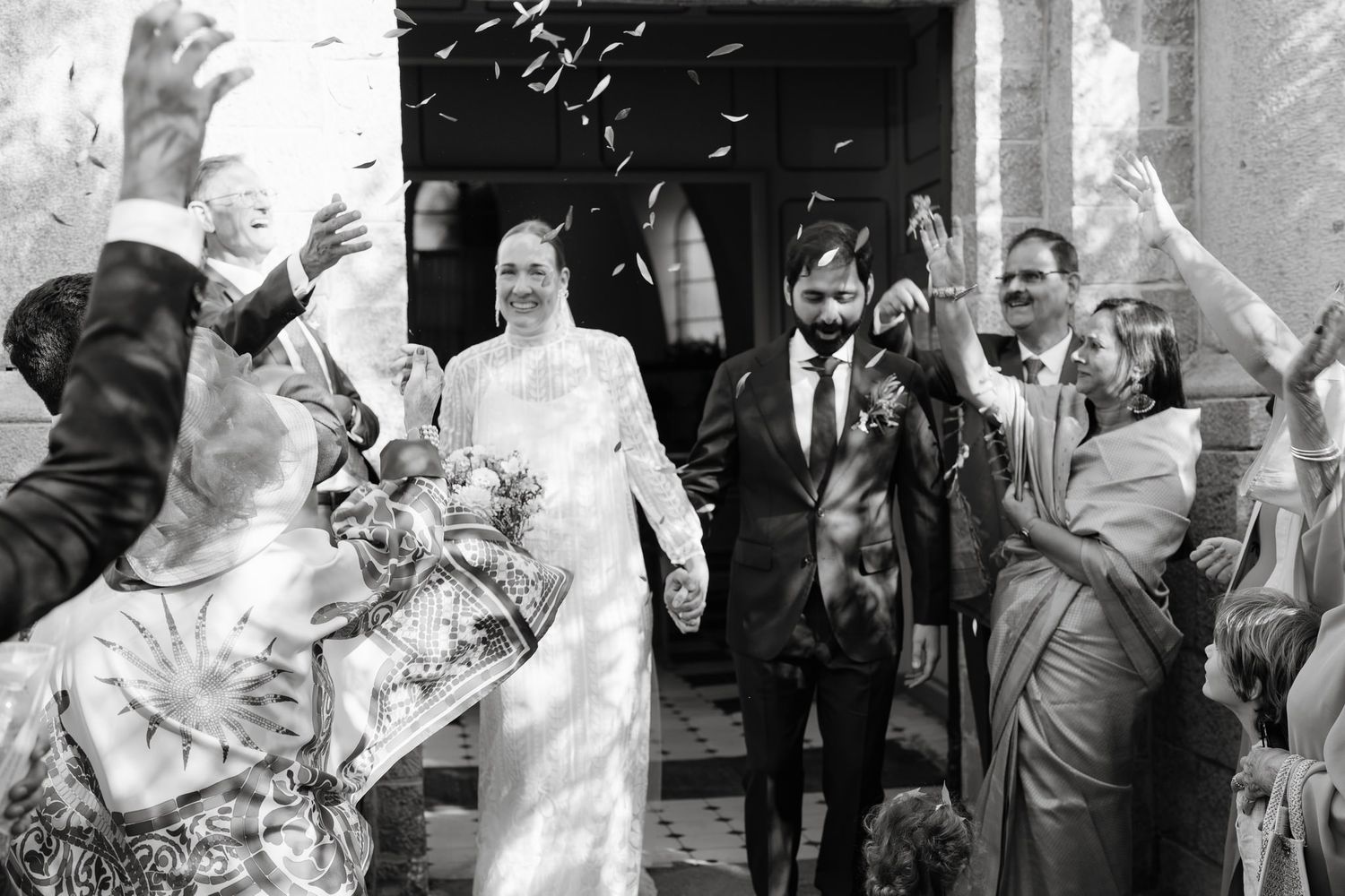 Black and white wedding celebration with guests throwing confetti at the happy couple.