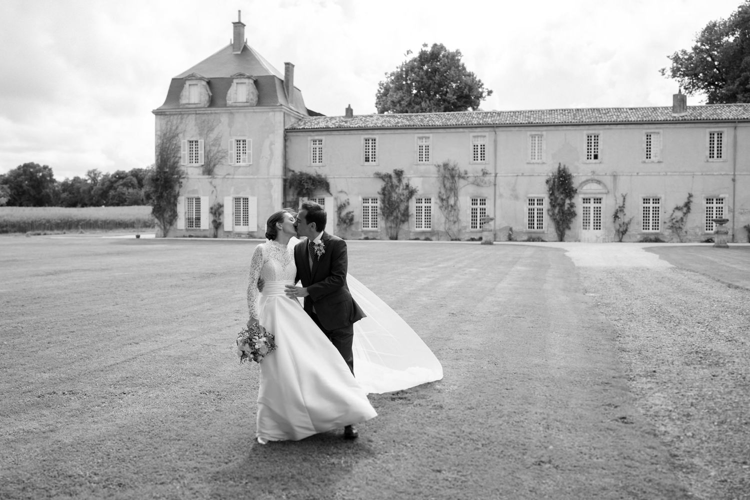 Wedding couple poses in front of a majestic French chateau on their special day.