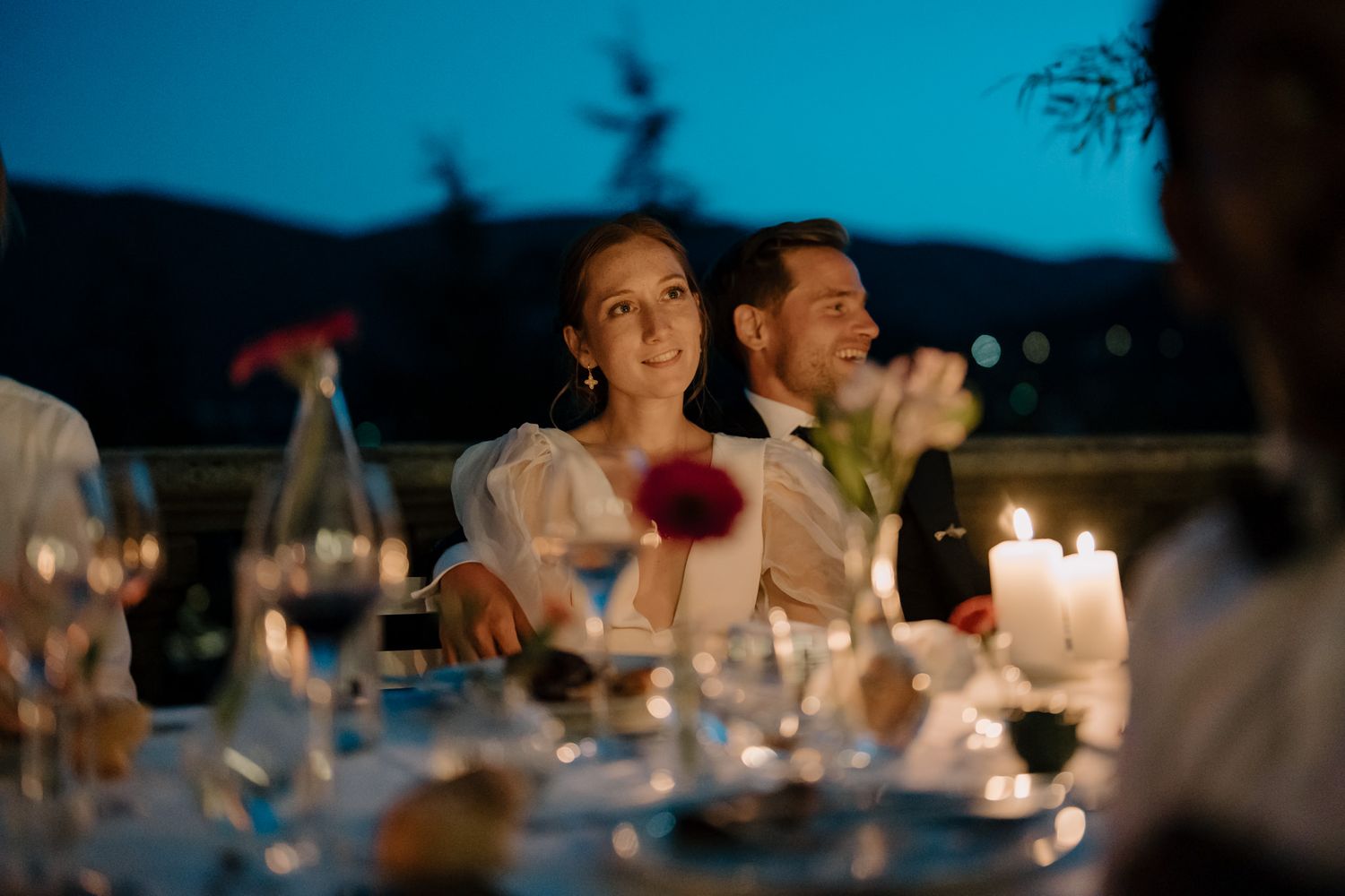 Intimate dinner reception under blue twilight sky with candlelight ambiance.