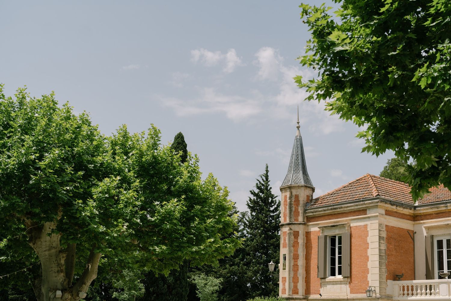 Exterior view of a brick church building with steeple under blue summer sky.