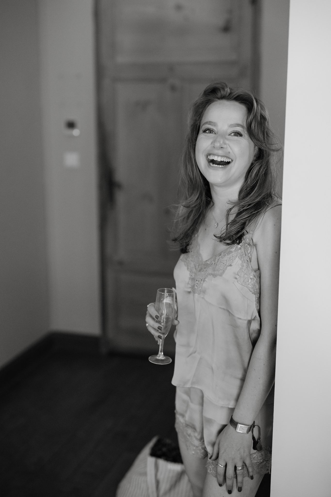 Black and white portrait of person laughing with champagne glass.