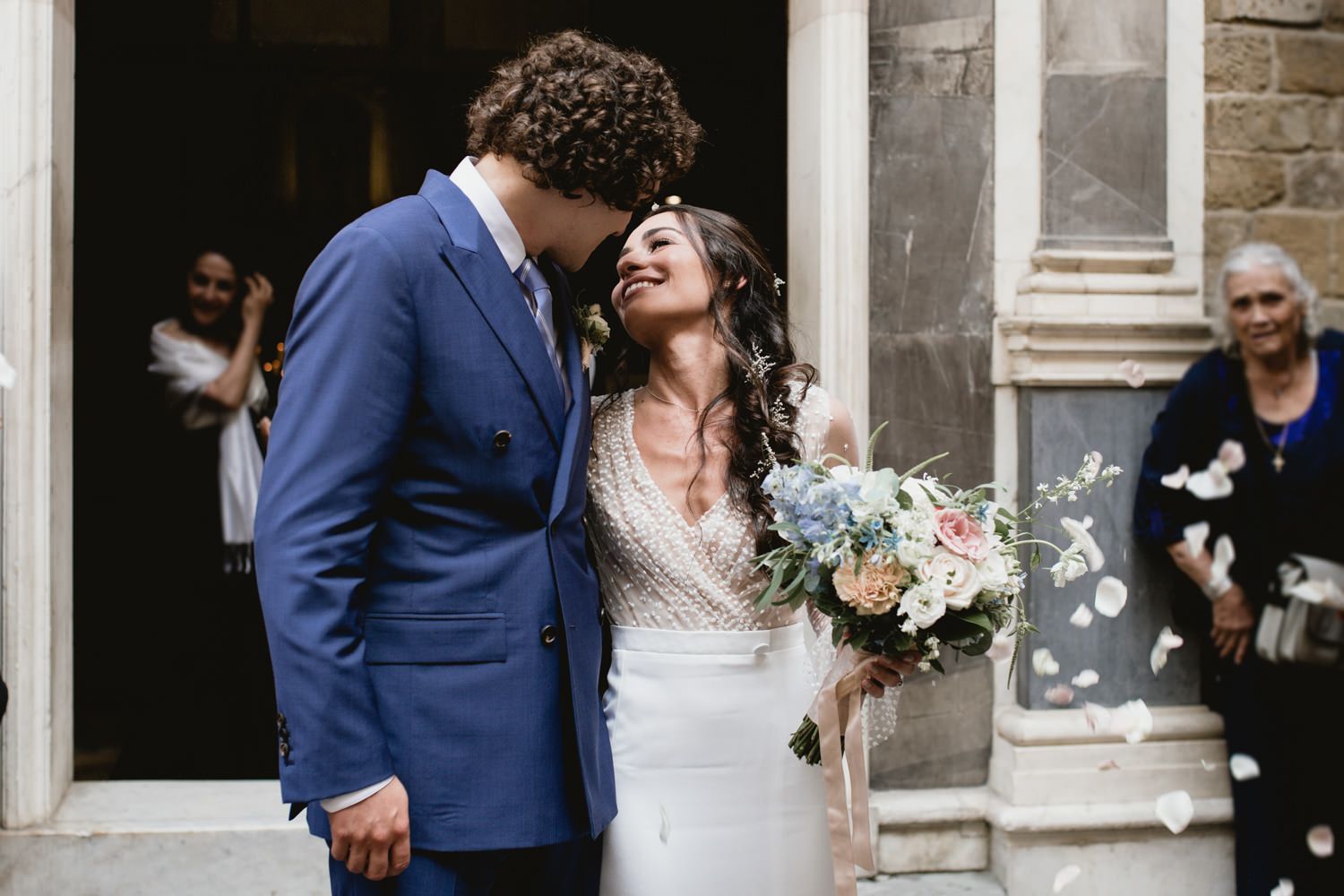 Candid wedding moments captured outside historic stone church building.