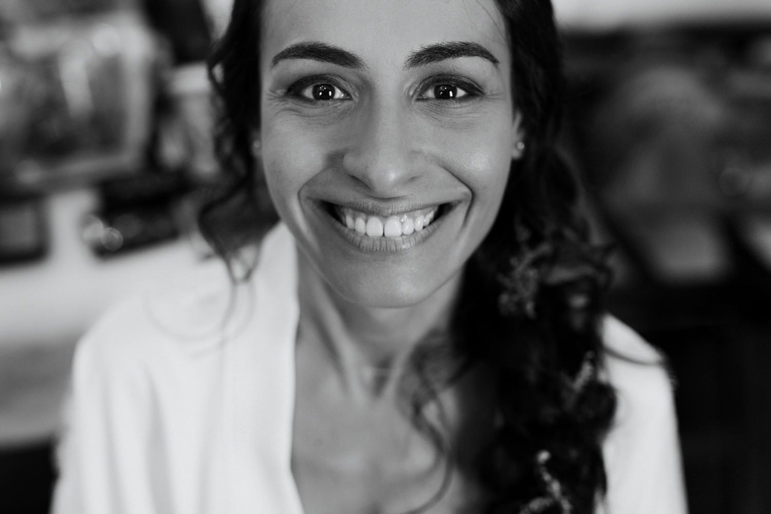 Black and white portrait showing a bright genuine smile and curly hair.