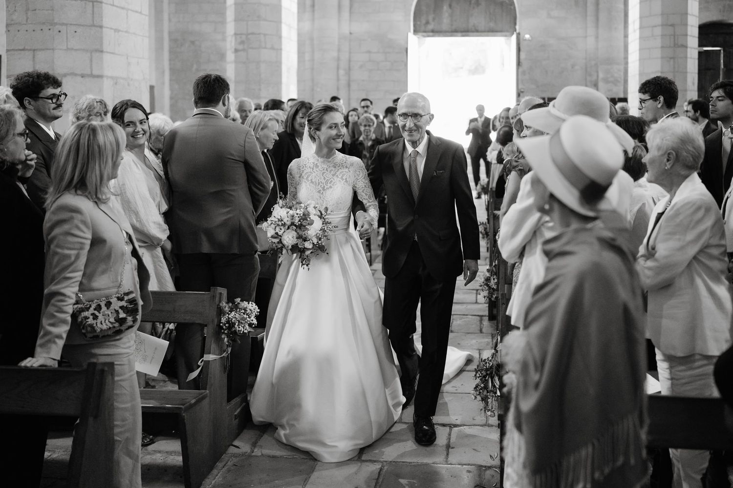 Black and white photo of wedding ceremony exit with guests lining the church aisle.