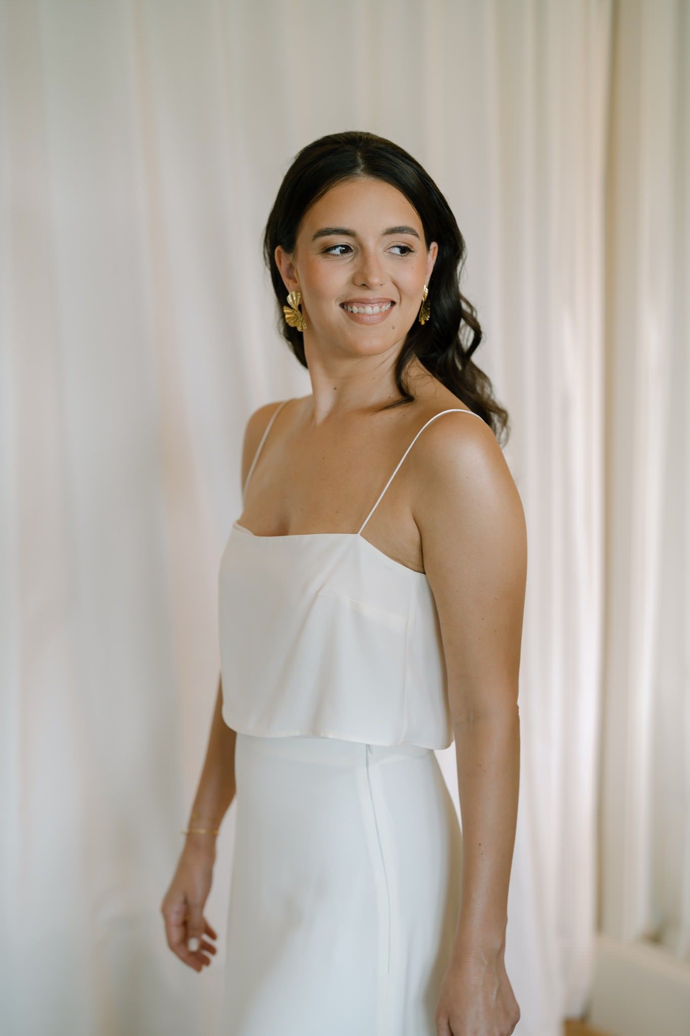 Person in a white sleeveless dress against a light backdrop.