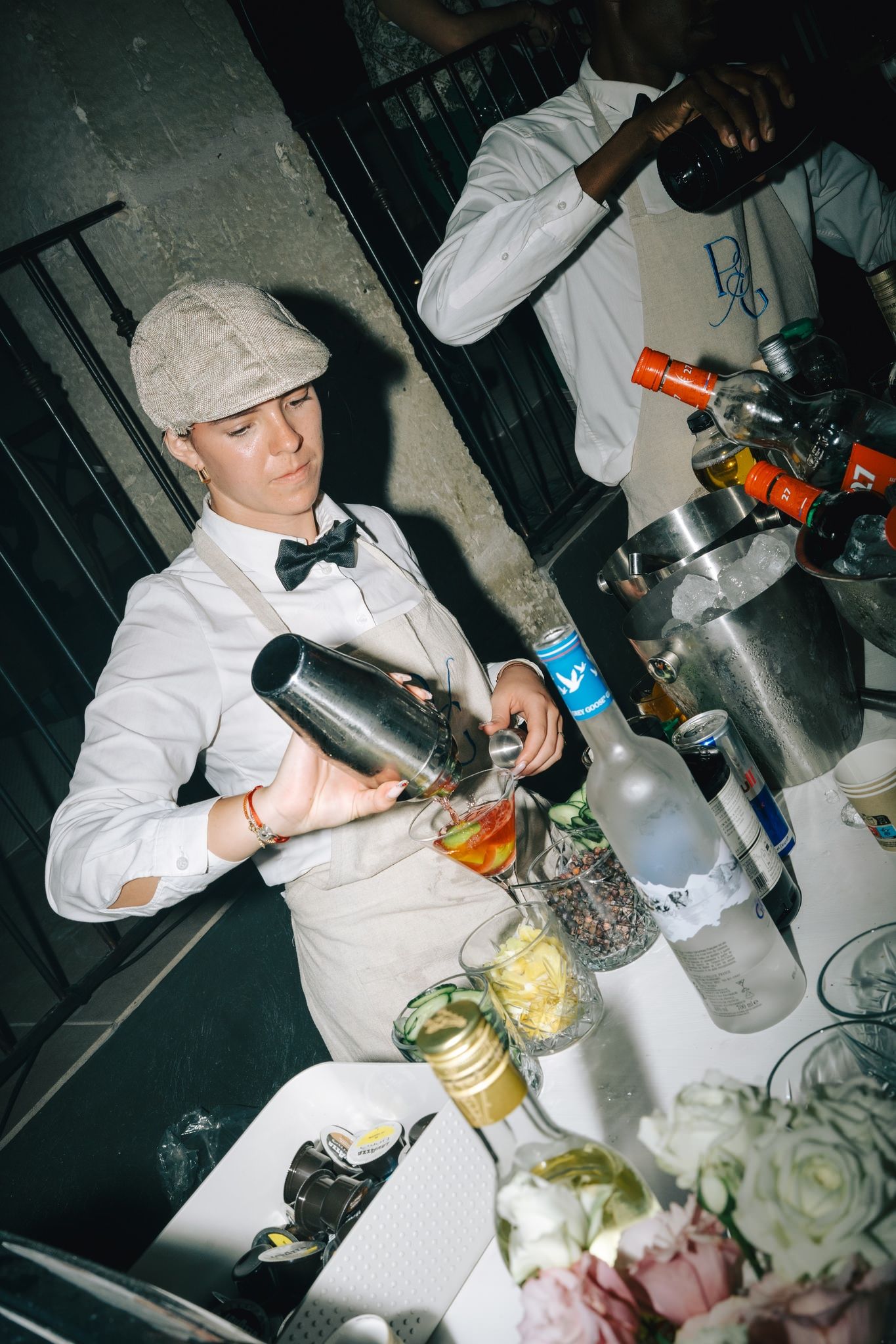 Chef in white uniform preparing food and drinks at an elegant catering station.