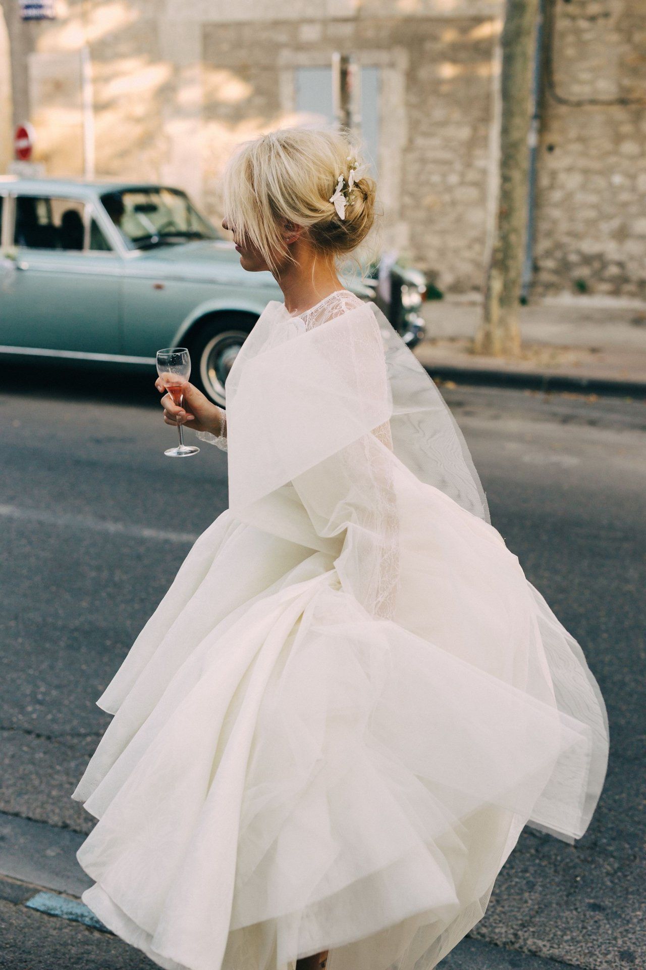 Bride in flowing white dress twirling on urban street.