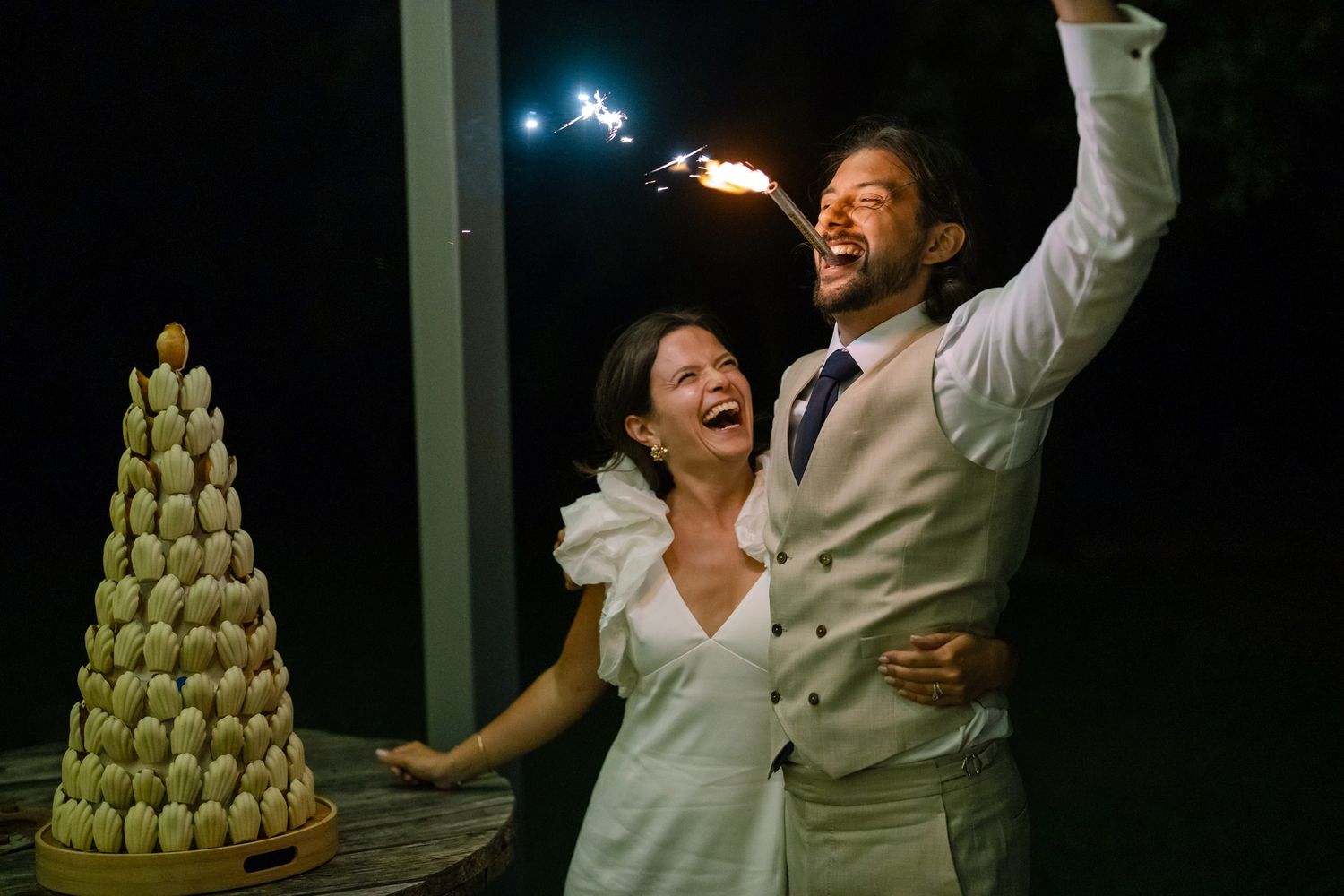 Celebratory moment with sparklers and a macaron tower at night.