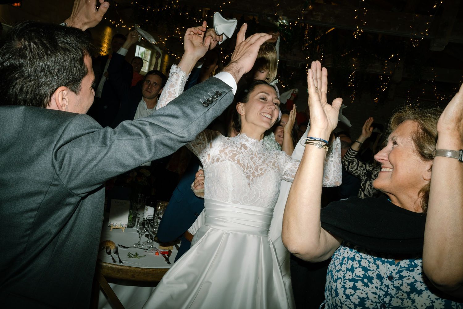 Guests dancing and celebrating at a dimly lit wedding reception.