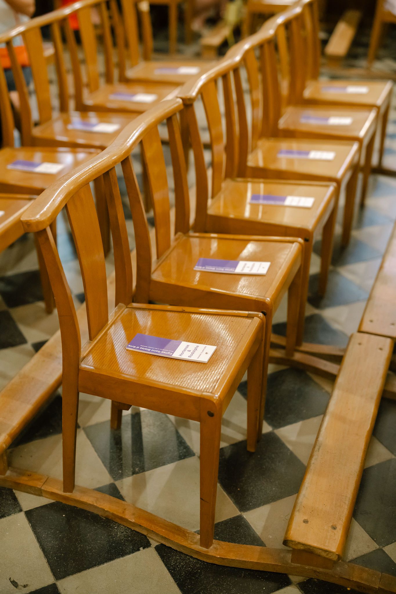 Rows of wooden chairs with blue programs arranged in a church or ceremony space.