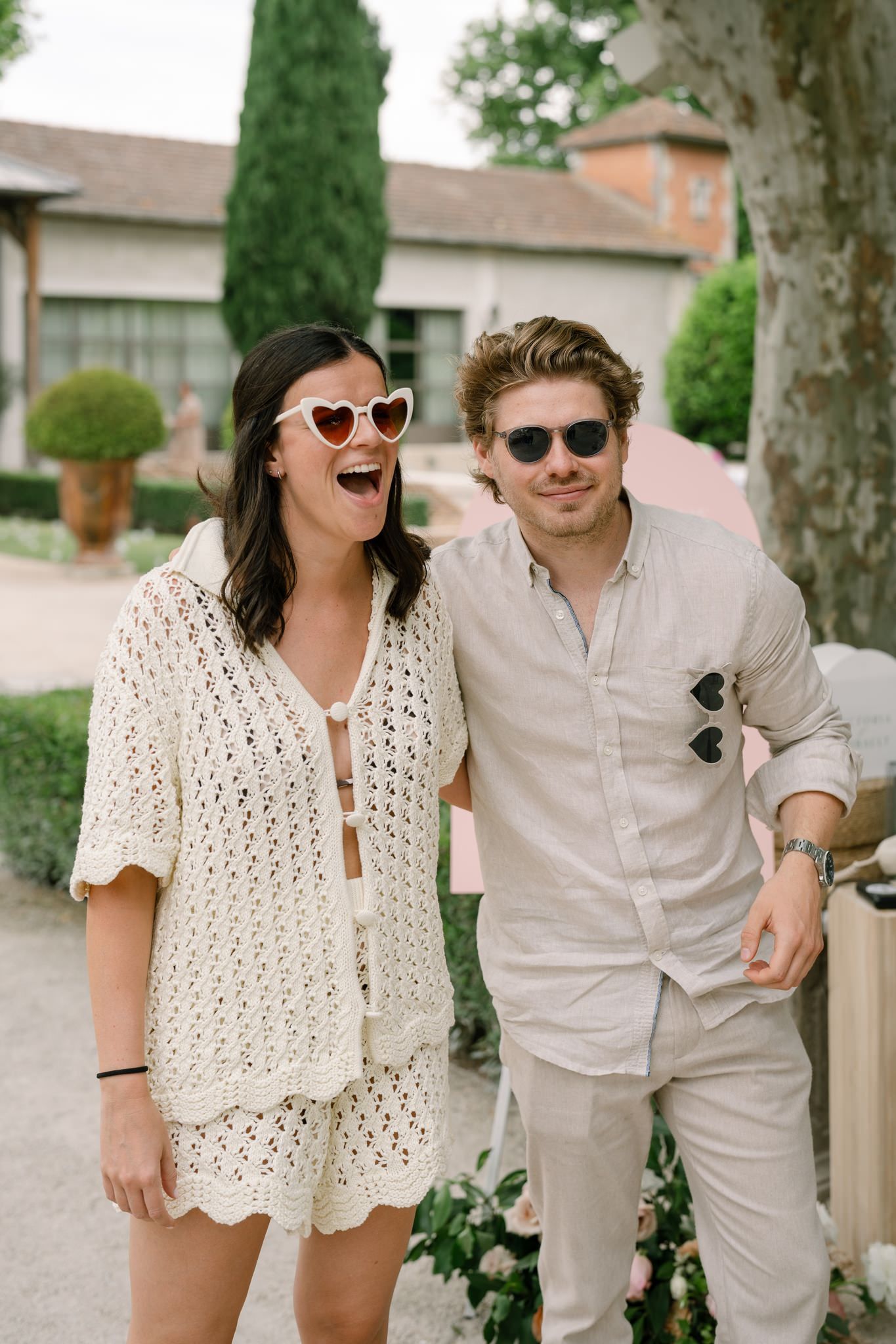 Couple in coordinated cream and white summer outfits posing together outdoors.