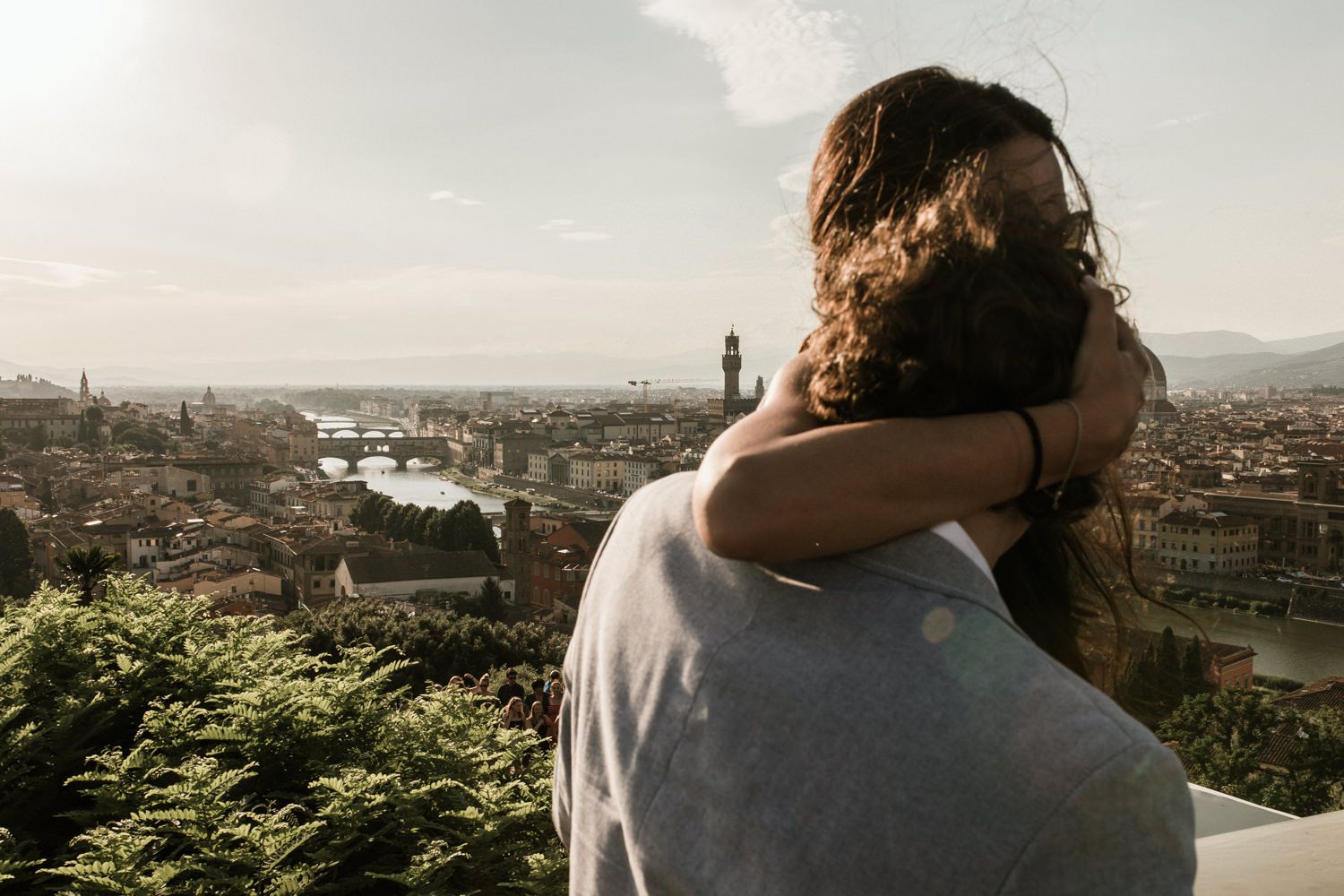 Couple embraces while overlooking a scenic cityscape view during golden hour.