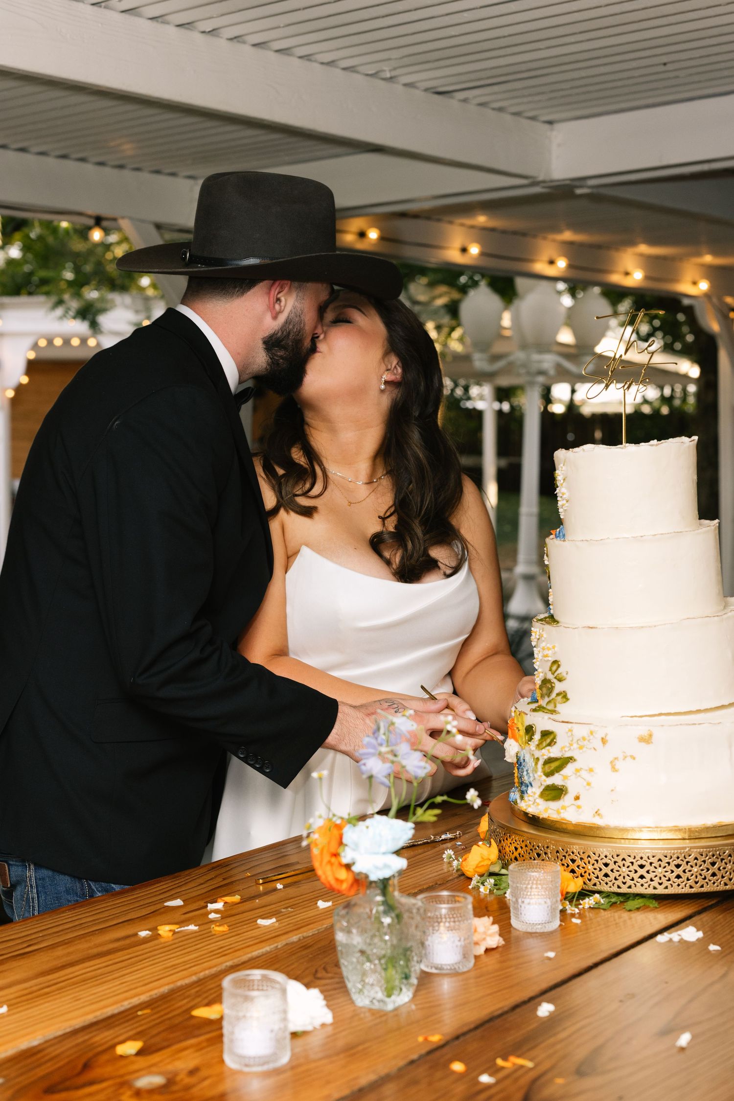 Romantic wedding cake cutting scene with a couple sharing a tender moment beside their elegant white tiered cake.