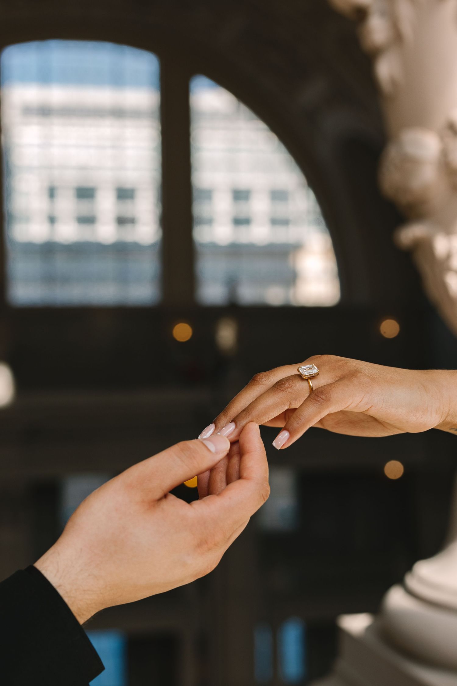 Close-up of hands exchanging an engagement ring during a romantic proposal.