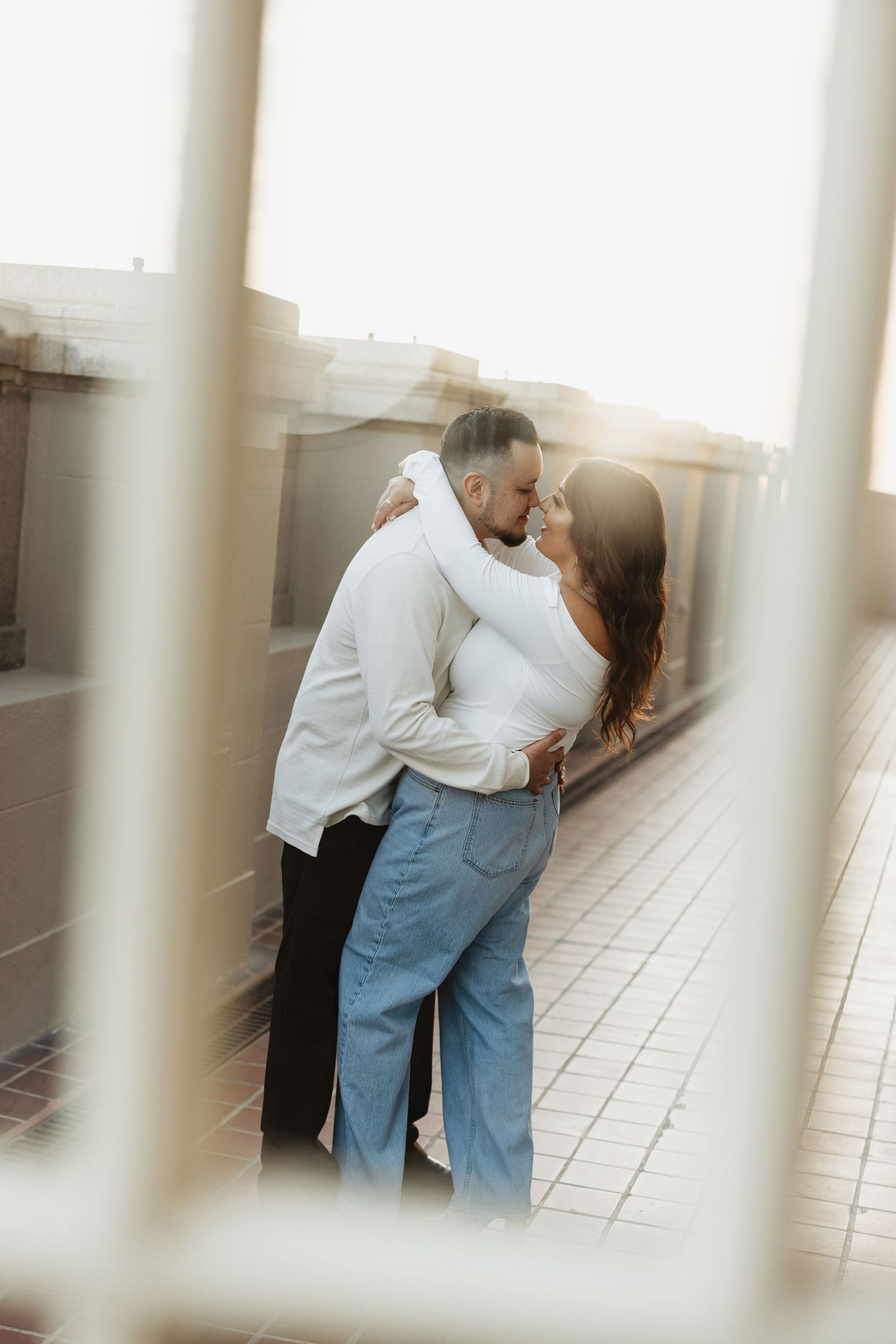 Intimate moment captured through architectural columns with soft dreamy lighting.