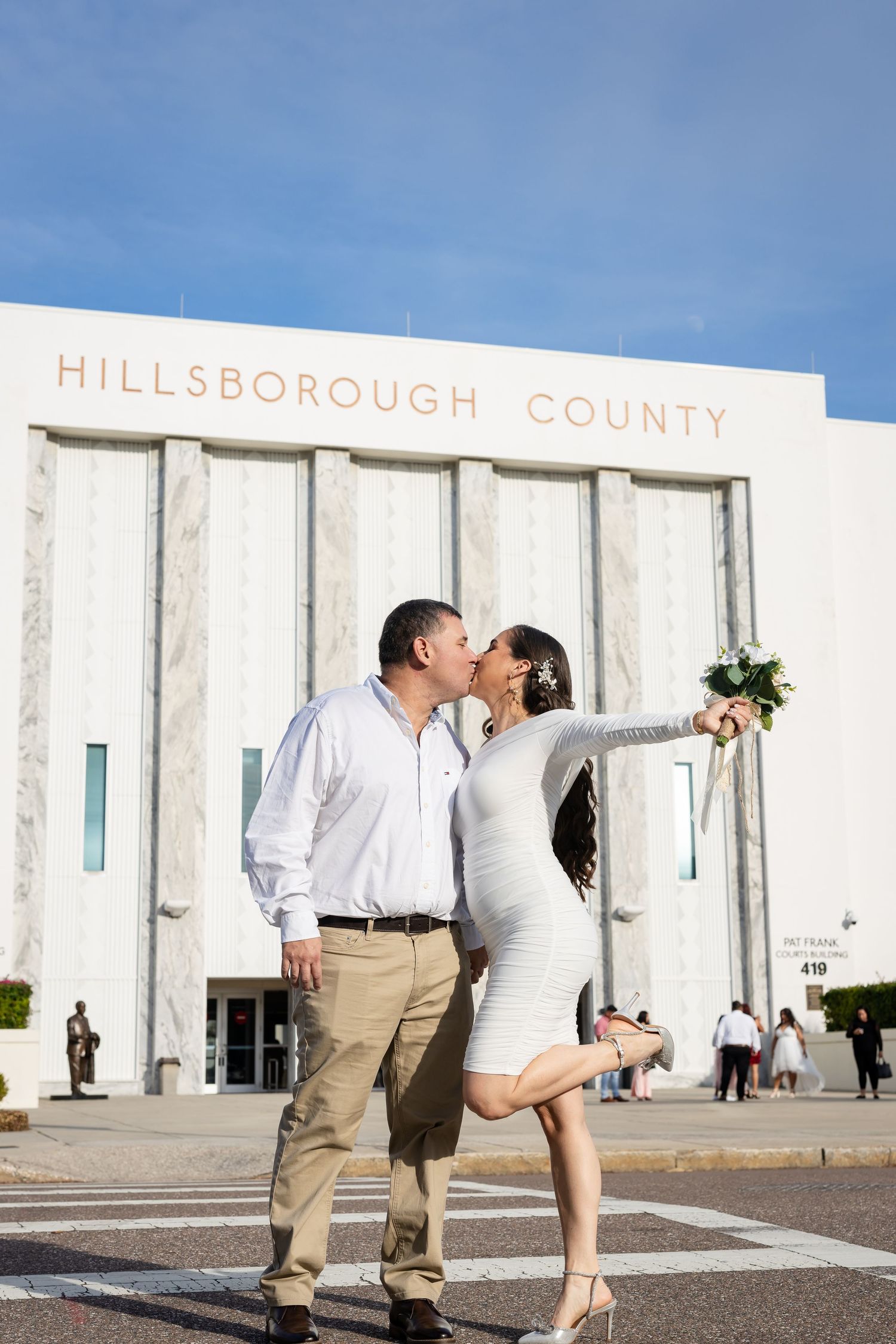 Three sequential shots of a couple sharing a romantic kiss in front of a minimalist white building exterior.